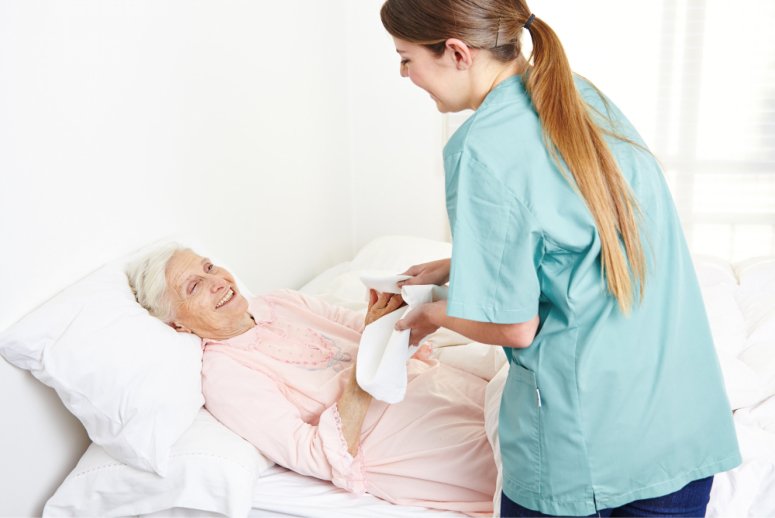 A compassionate caregiver gently holding a senior's hand in a peaceful home